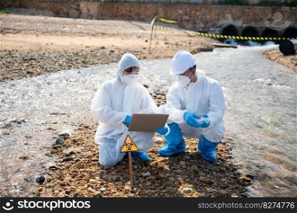 Biologist wear protective suit and mask collects sample of waste water from industry, problem environment, Ecologist sample taken dead fish to inspection and save data to laptop computer, Toxic water