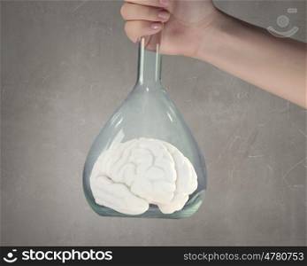 Biology research and experiment. Hand holds flask with image of human brain