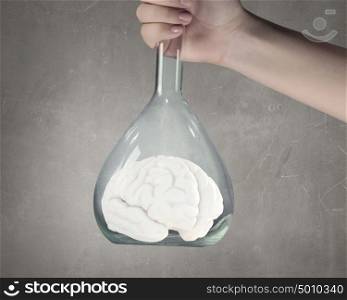 Biology research and experiment. Hand holds flask with image of human brain