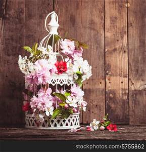 Bird cage with spring blossom of sakura and fruit flowers. Wedding decorations with copy space. Bird cage with wooden heart
