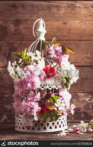 Bird cage with spring blossom of sakura and fruit flowers. Wedding decorations with copy space. Bird cage with wooden heart