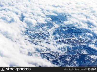 Bird's eye view on snowy mountains, scene on the mountain through white fluffy clouds, winter holidays, cold weather&#xA;