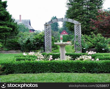 Birdbath and arbour in country garden.