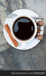 Birds eye view of hot coffee on slate background with cinnamon sticks, nutmeg and star anise
