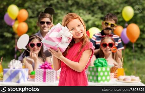 birthday and people concept - lovely red haired girl with gift box over party at summer park. lovely red haired girl with birthday gift at party
