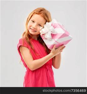 birthday and people concept - lovely red haired girl with gift box over grey background. lovely red haired girl with birthday gift