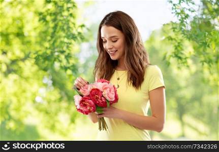 birthday and people concept - smiling young woman or teenage girl in yellow t-shirt with flower bouquet over green natural background. young woman or teenage girl with flower bouquet