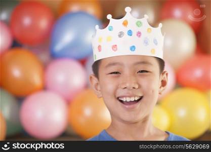 Birthday Boy Wearing a Crown in Front of Balloons