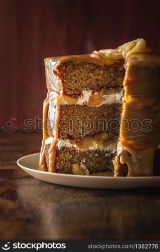 Birthday cake interior with sponge cake layers, yogurt filling, and apples, with caramel glaze. Sliced layered cake. Festive dessert with apples.