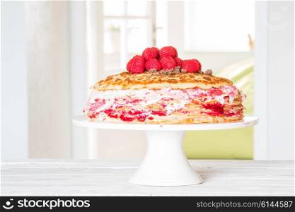 Birthday cake with pancakes and raspberries in a bright room