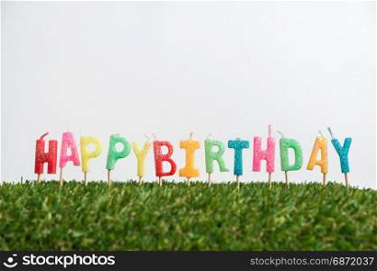 Birthday candles with grass on white background