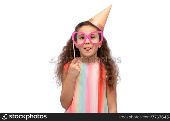 birthday, childhood and people concept - portrait of little girl in dress and party hat with glasses over white background. little girl in birthday party hat with glasses