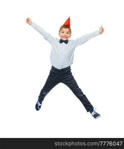 birthday, childhood and people concept - portrait of smiling little boy in dress and party hat jumping over white background. smiling little boy in birthday party hat jumping