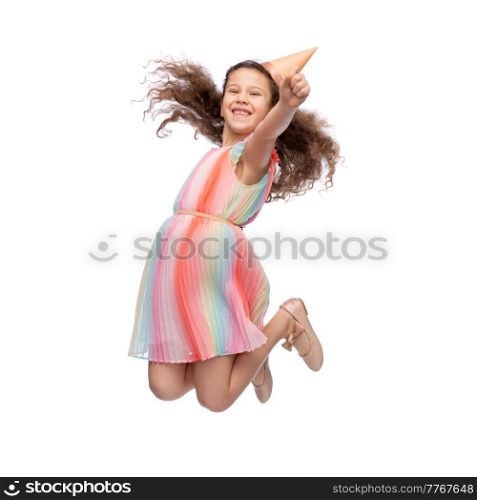 birthday, childhood and people concept - portrait of smiling little girl in dress and party hat jumping over white background. smiling little girl in birthday party hat jumping