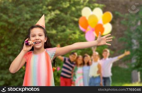 birthday, childhood and people concept - portrait of smiling little girl in party hat with blower having fun over group of children at summer park background. happy girl with blower on birthday party at park