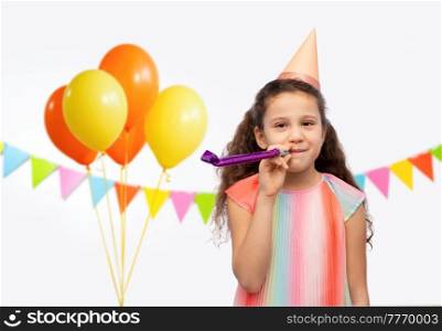 birthday, childhood and people concept - portrait of smiling little girl in party hat with blower over balloons and flags on white background. smiling girl in birthday party hat with blower