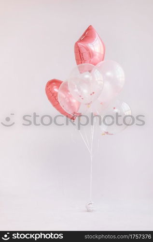 Birthday decorations with white and pink color balloons and confetti for party on a white wall. Happy birthday.. Birthday decorations with white and pink color balloons and confetti for party on a white wall. Happy birthday