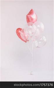 Birthday decorations with white and pink color balloons and confetti for party on a white wall. Happy birthday.. Birthday decorations with white and pink color balloons and confetti for party on a white wall. Happy birthday