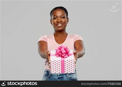 birthday present and people concept - happy african american young woman with gift box over pink background. happy african american woman with birthday present