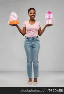 birthday present and surprise concept - happy african american young woman with gift boxes over grey background. happy african american woman with gift boxes