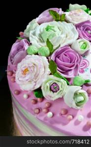 biscuit cake layered with mascarpone cream and berry cream and mastic flowers on dark