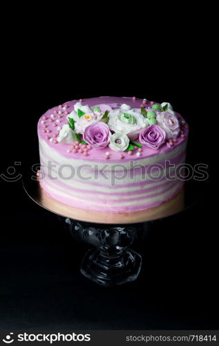 biscuit cake layered with mascarpone cream and berry cream and mastic flowers on dark