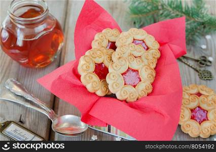 Biscuit Christmas cookies with red jam in the tin box on an old wooden table