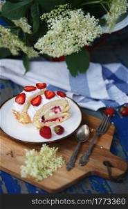 biscuit roll with strawberries. a piece of dessert on a plate. rose and strawberry for decoration