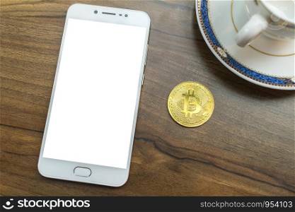 Bitcoin coin and Smartphone, Pen and Coffee cup on old wood desk on top.