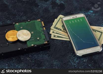 Bitcoin coin with HDD money and smartphone. Bitcoin coins with HDD, money and smartphone with diagrams on screen on a dark background