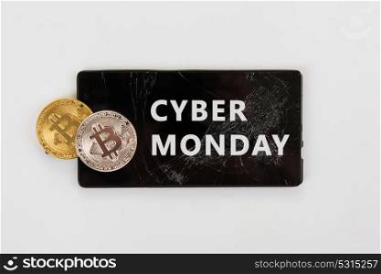 Bitcoin coins on the broken phone with Cyber Monday sign. Bitcoin Cyber Monday