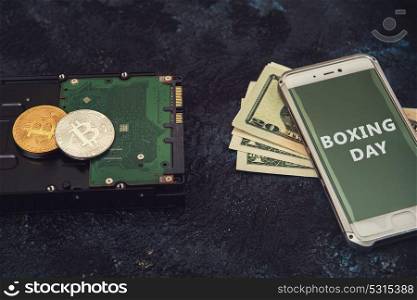 Bitcoin coins on the HDD and phone with Boxing day sign. Bitcoin Boxing day