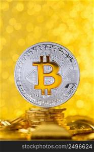 Bitcoin with bit symbol on top of gold coin stack with shiny golden background