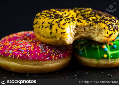 Bitten yellow glazed donut with sprinkles isolated. Close up of colorful donuts.