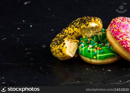 Bitten yellow glazed donut with sprinkles isolated. Close up of colorful donuts.