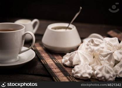 bizet on a brown wooden table with a cup of tea, sugar and milk