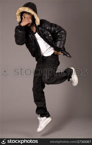 Black acrobat man dancing in studio on grey background
