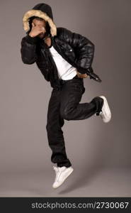 Black acrobat man dancing in studio on grey background