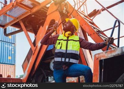Black African male worker work as port cargo manager using radio control loading container in logistic industry.