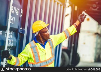Black African worker working in logistic shipping radio control order command loading containers at shipping port. staff cargo for import export goods logistic.