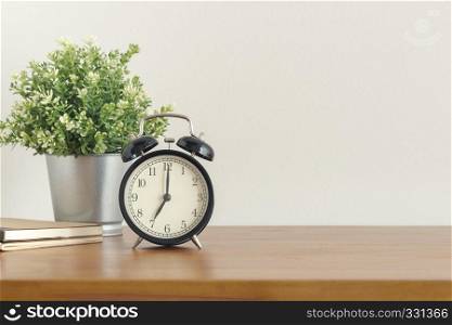 Black alarm clock on wooden desk on white background