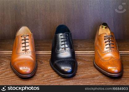 Black and brown full grain leather shoes on wooden display in men shoes boutique store.. men footwear boutique store