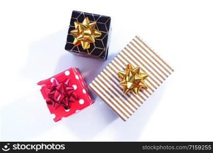 Black and gold, red and white polka dots and white and gold three gift boxes with gold and red bows on a white background.