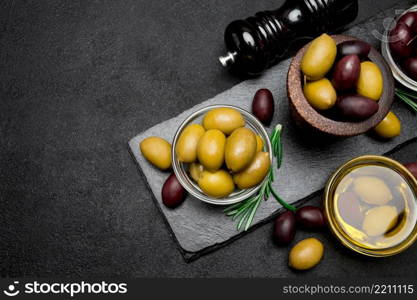 black and green olives and oil on stone serving board, dark concrete background. black and green olives and oil on stone serving board