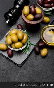 black and green olives and oil on stone serving board, dark concrete background. black and green olives and oil on stone serving board