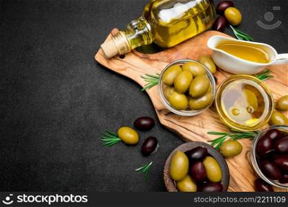black and green olives and oil on wooden cutting board, dark concrete background. black and green olives and oil on wooden cutting board