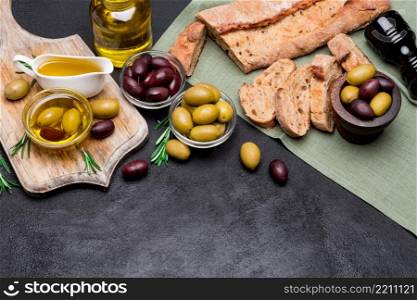 black and green olives, bread and n wooden cutting board, dark concrete background. black and green olives, bread and n wooden cutting board