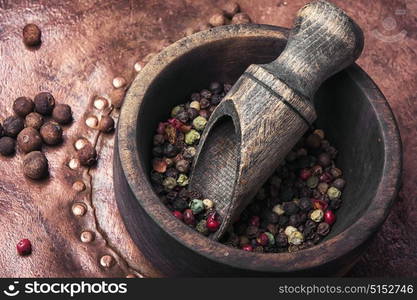 Black and red pepper peas in a wooden mortar. Spice pepper peas