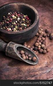 Black and red pepper peas in a wooden mortar. Spice pepper peas