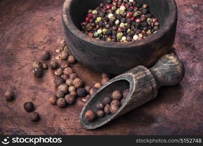Black and red pepper peas in a wooden mortar. Spice pepper peas